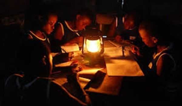 Students reading under lantern - a sign of power outage known as Dumsor in Ghana