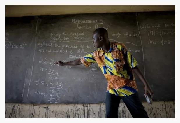 A teacher pointing to a text on the blackboard